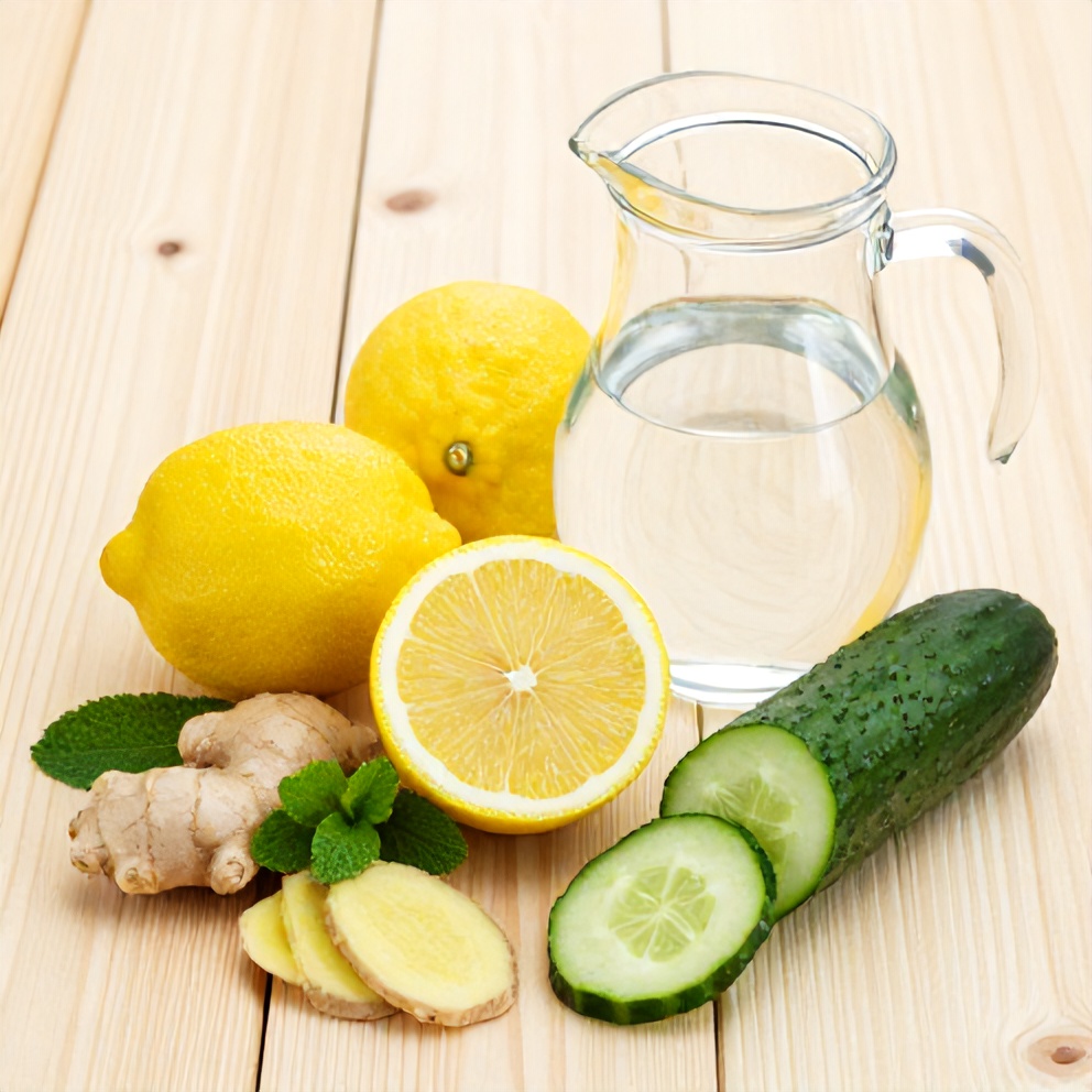 Lemons, ginger, cucumber, mint, and water on a wooden surface